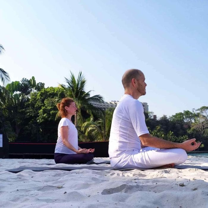 Maggie and Brad meditating on the beach in Thailand
